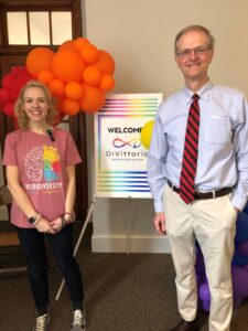 Sen. Hutchinson standing with a constituent in front of a sign that says Welcom DiVittorio Center for Autism with colorful balloons in the background.
