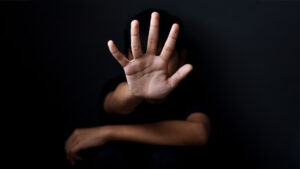 Women in dark room with hand thrust forward.
