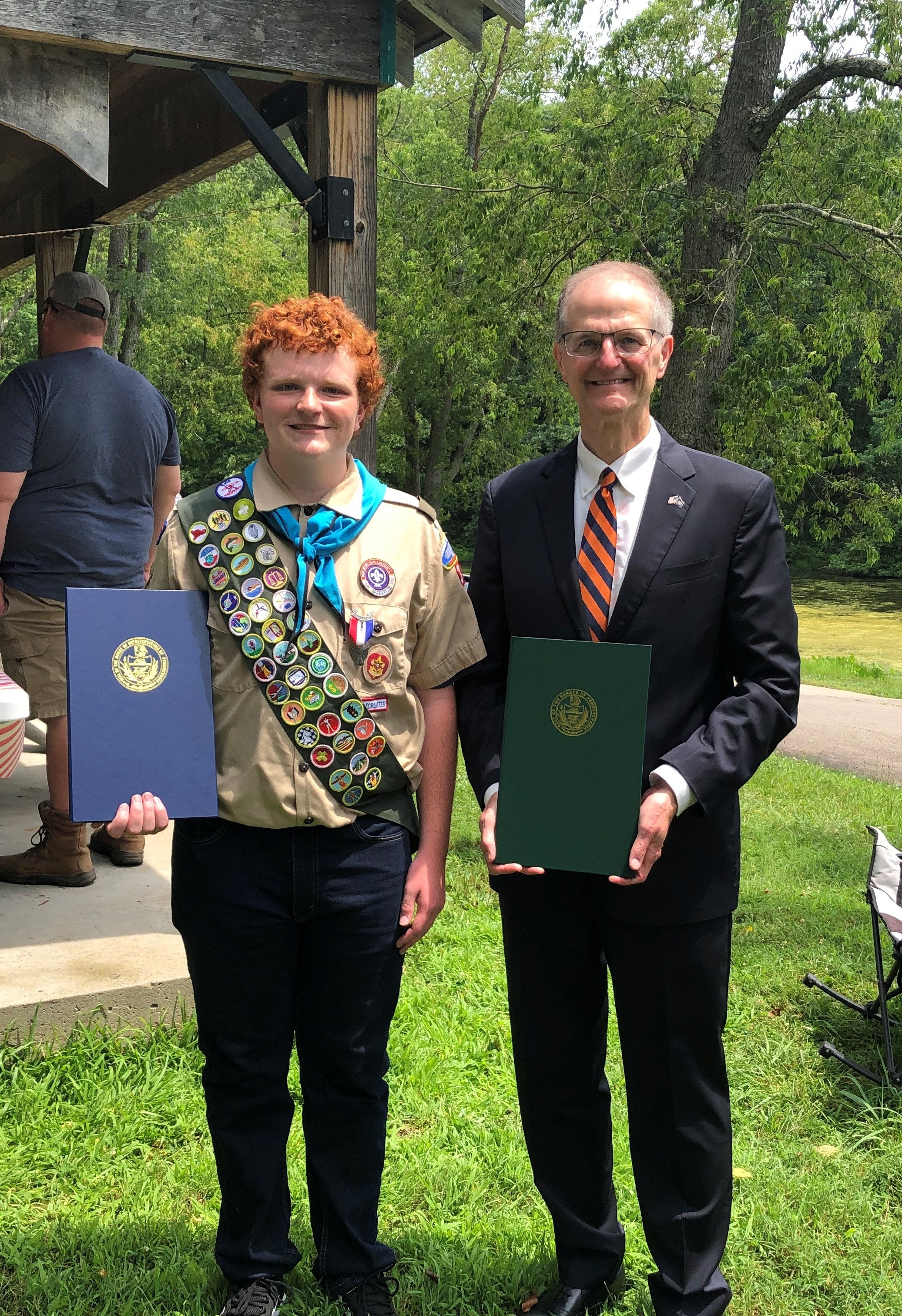 Senator Hutchinson Alt Text Eagle Scout smiling at camera and holding House and Senate citations.